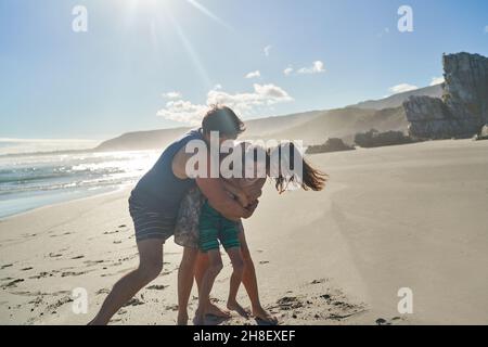 Happy playful family hugging on sunny summer beach Stock Photo
