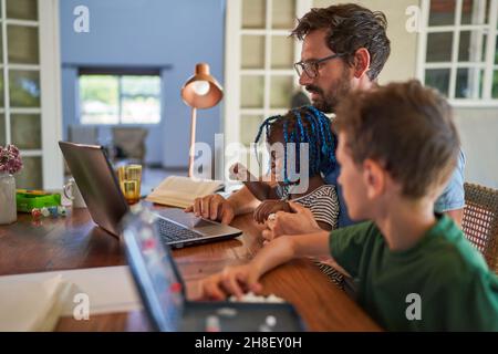 Father working from home at laptop with daughter on lap Stock Photo