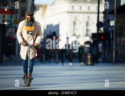 Businessman riding electric push scooter on city street Stock Photo