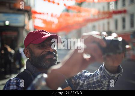 Male tourist using digital camera on sunny city street Stock Photo