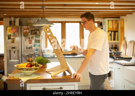 Man working at laptop standing desk in kitchen Stock Photo