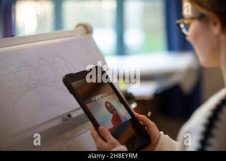 Female architect video chatting with colleague on digital tablet Stock Photo