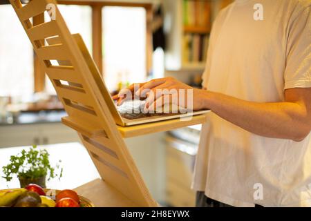 Man working from home at laptop stand desk Stock Photo