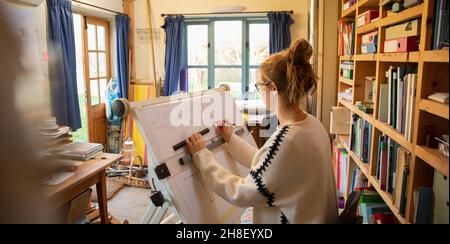 Female architect working at drafting table in home office Stock Photo