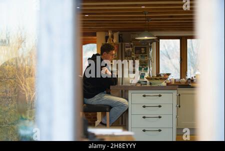 Man working from home at laptop on kitchen counter Stock Photo