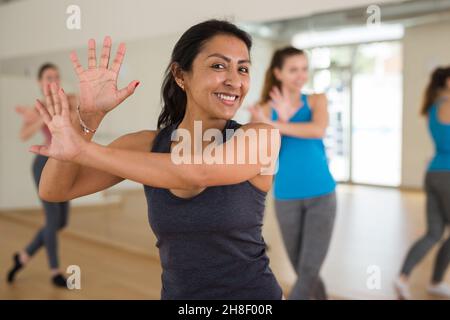Cheerful hispanic woman practicing vigorous dance in group class Stock Photo
