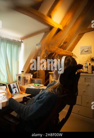 Woman video chatting with colleagues in home office Stock Photo