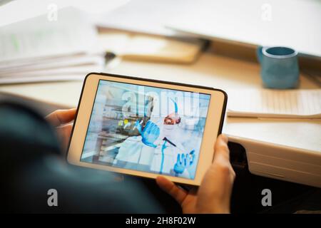 Man watching scientist with pipette on digital tablet screen Stock Photo