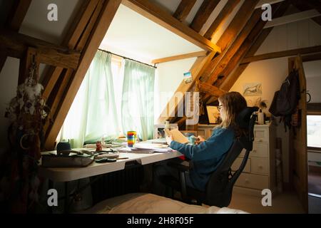 Woman reading book at desk in home office Stock Photo