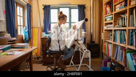 Female architect working at drafting table in home office Stock Photo