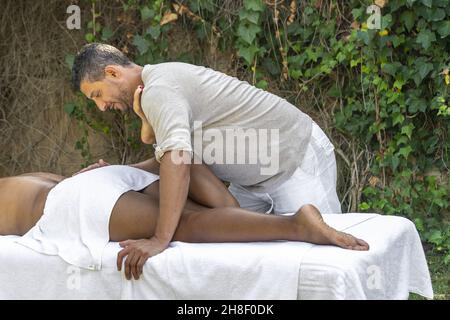 Spanish man massaging a woman's leg outdoors Stock Photo