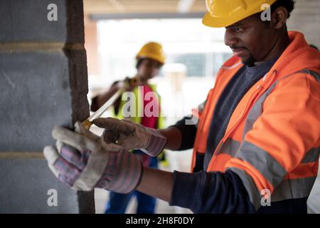 Construction workers using tape measure at construction site Stock Photo