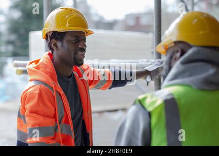 Male construction workers talking at construction site Stock Photo