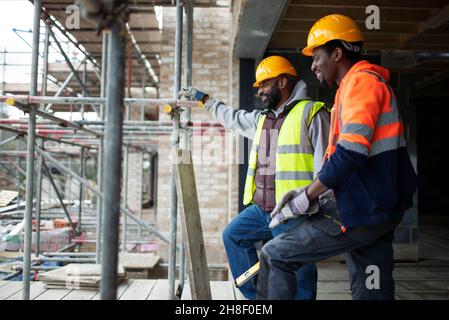 Male construction workers talking at construction site Stock Photo