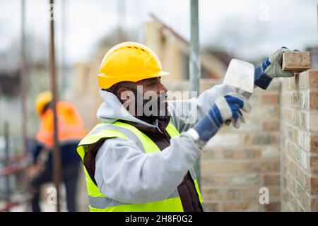 Male construction worker laying bricks at construction site Stock Photo