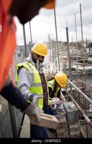 Construction workers laying bricks at construction site Stock Photo