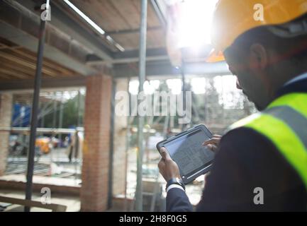 Male architect looking at digital blueprints at construction site Stock Photo