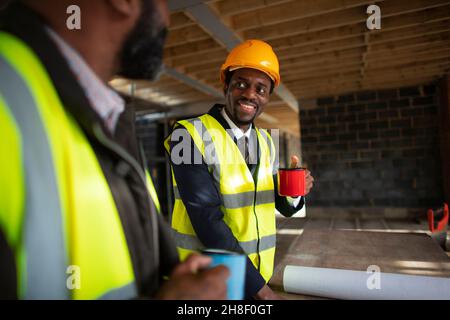 Male architects drinking coffee at construction site Stock Photo