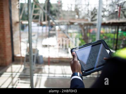 Engineer looking at blueprints on digital tablet at construction site Stock Photo
