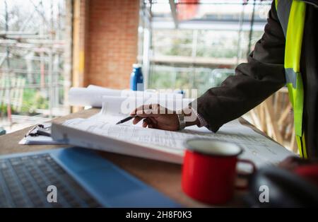 Male architect reviewing blueprints at construction site Stock Photo