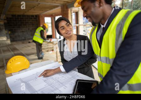 Architect and engineer reviewing blueprints at construction site Stock Photo