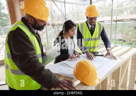 Architects and engineer looking at blueprints at construction site Stock Photo