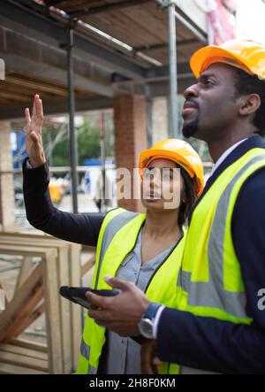 Engineers with digital tablet talking at construction site Stock Photo