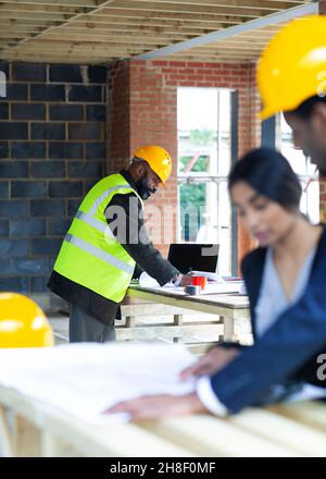 Architects reviewing blueprints at construction site Stock Photo