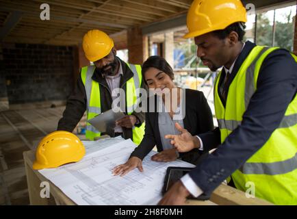 Architects and engineer discussing blueprints at construction site Stock Photo