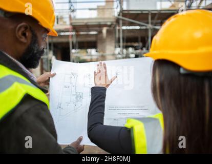 Architects with blueprints at construction site Stock Photo