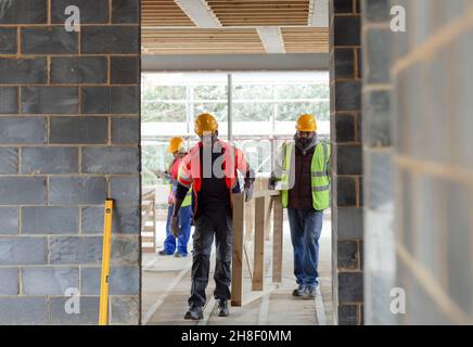 Construction workers carrying wood frame at construction site Stock Photo