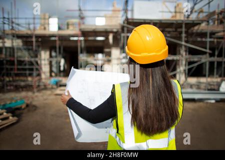 Female architect reviewing blueprints at construction site Stock Photo