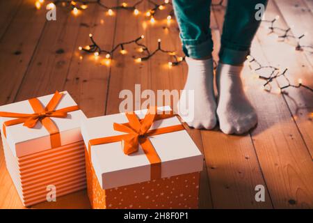 red gift boxes  feet and christmas lights on wooden floor Stock Photo
