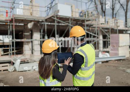 Engineers with digital tablet at sunny construction site Stock Photo