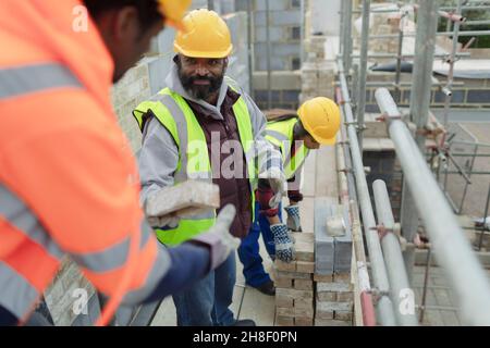 Construction workers laying brick at construction site Stock Photo