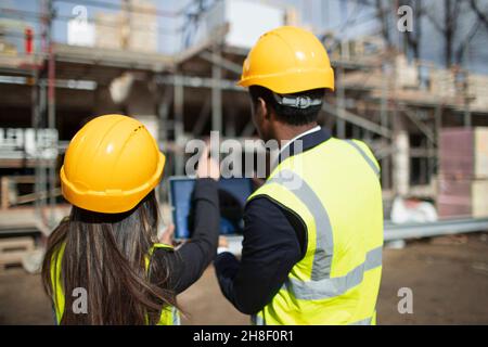 Engineer and architect with digital tablet at sunny construction site Stock Photo