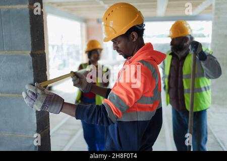 Construction workers with tape measure at construction site Stock Photo