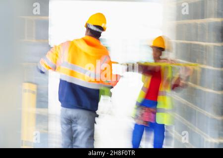 Construction workers with tape measure at construction site Stock Photo