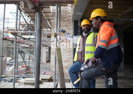 Male construction workers talking at construction site Stock Photo