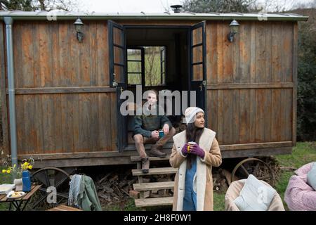 Couple enjoying coffee outside tiny cabin rental Stock Photo