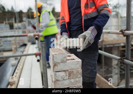 Construction worker laying bricks at construction site Stock Photo