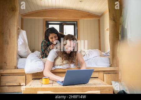 Happy young couple using laptop in tiny cabin bed Stock Photo