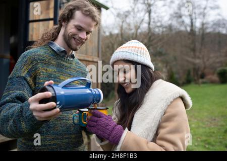 Young couple pouring coffee at campsite Stock Photo