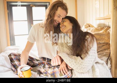 Happy young couple cuddling in bed Stock Photo