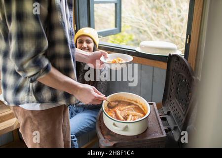 Happy young couple making stew in tiny cabin rental Stock Photo