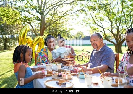 Multigenerational family celebrating birthday in summer backyard Stock Photo