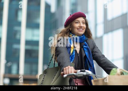 Happy young woman in beret riding bicycle Stock Photo