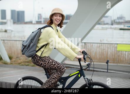 Portrait stylish young woman riding bicycle in city Stock Photo