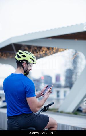 Man on bicycle using smart phone in city Stock Photo
