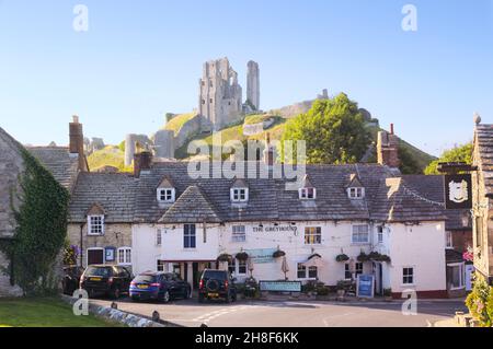 Corfe Castle village and the Greyhound Inn overlooked by the famous 11th century ruins of Corfe Castle, Isle of Purbeck, Dorset, England, UK Stock Photo